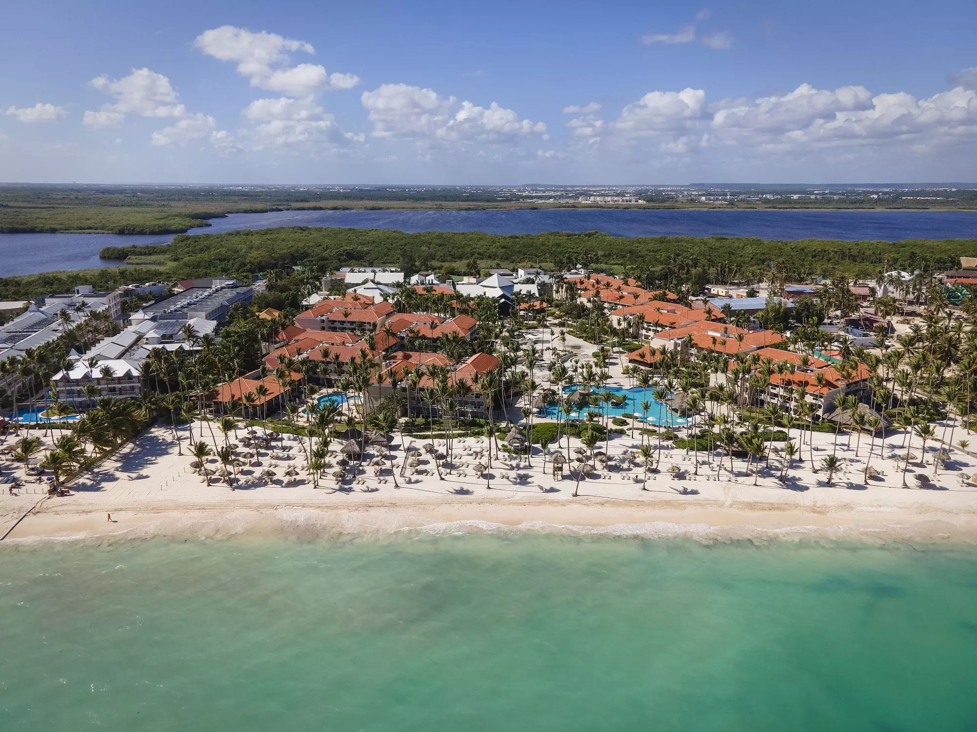 Aerial view of Hyatt Vivid Punta Cana beachfront resort with pools, palm trees, and turquoise Caribbean waters.